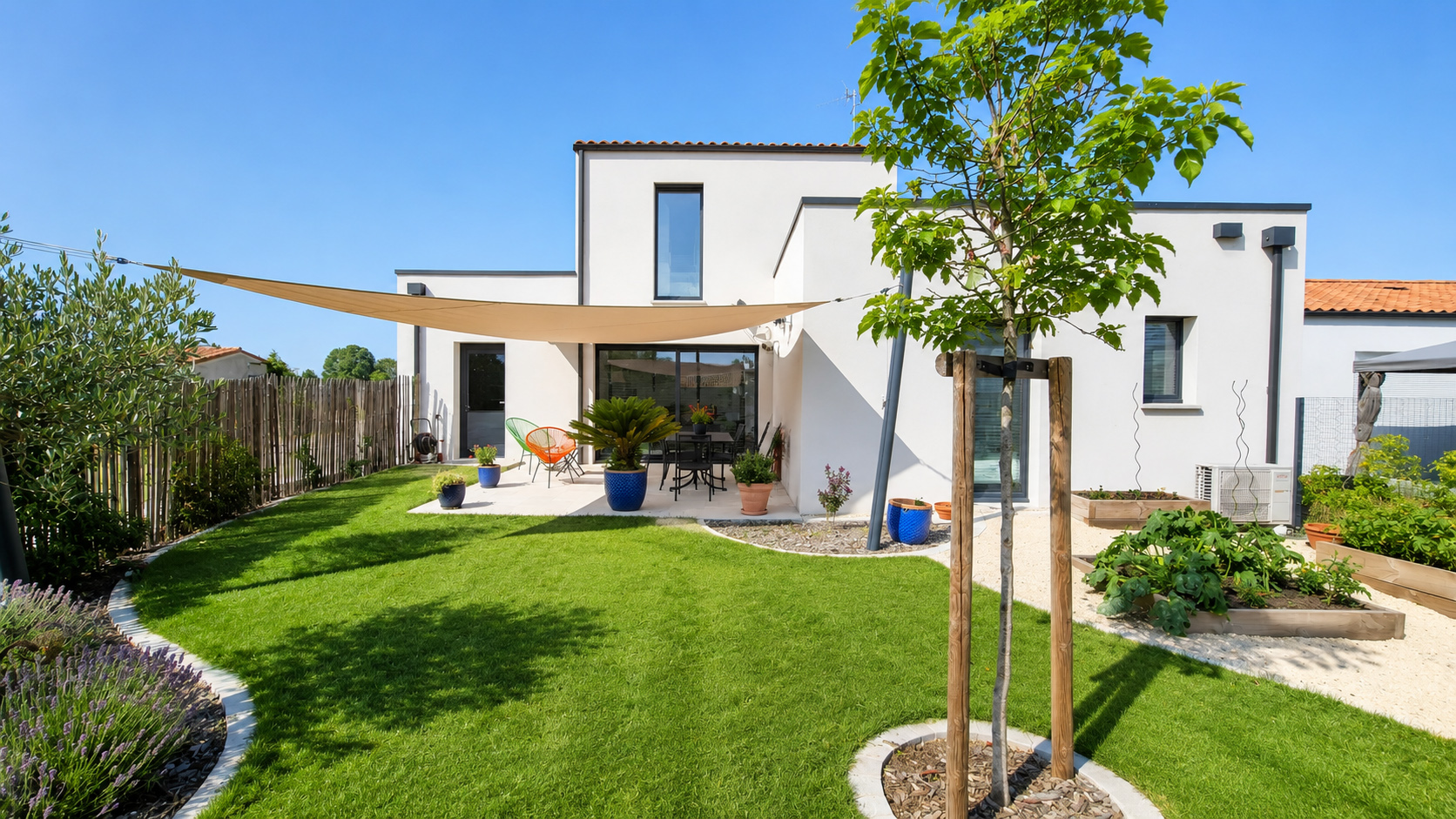 Construction d'une maison contemporaine avec terrasse aménagée, voile d'ombrage et jardin paysager réalisée par DV Archi Design en Vendée.